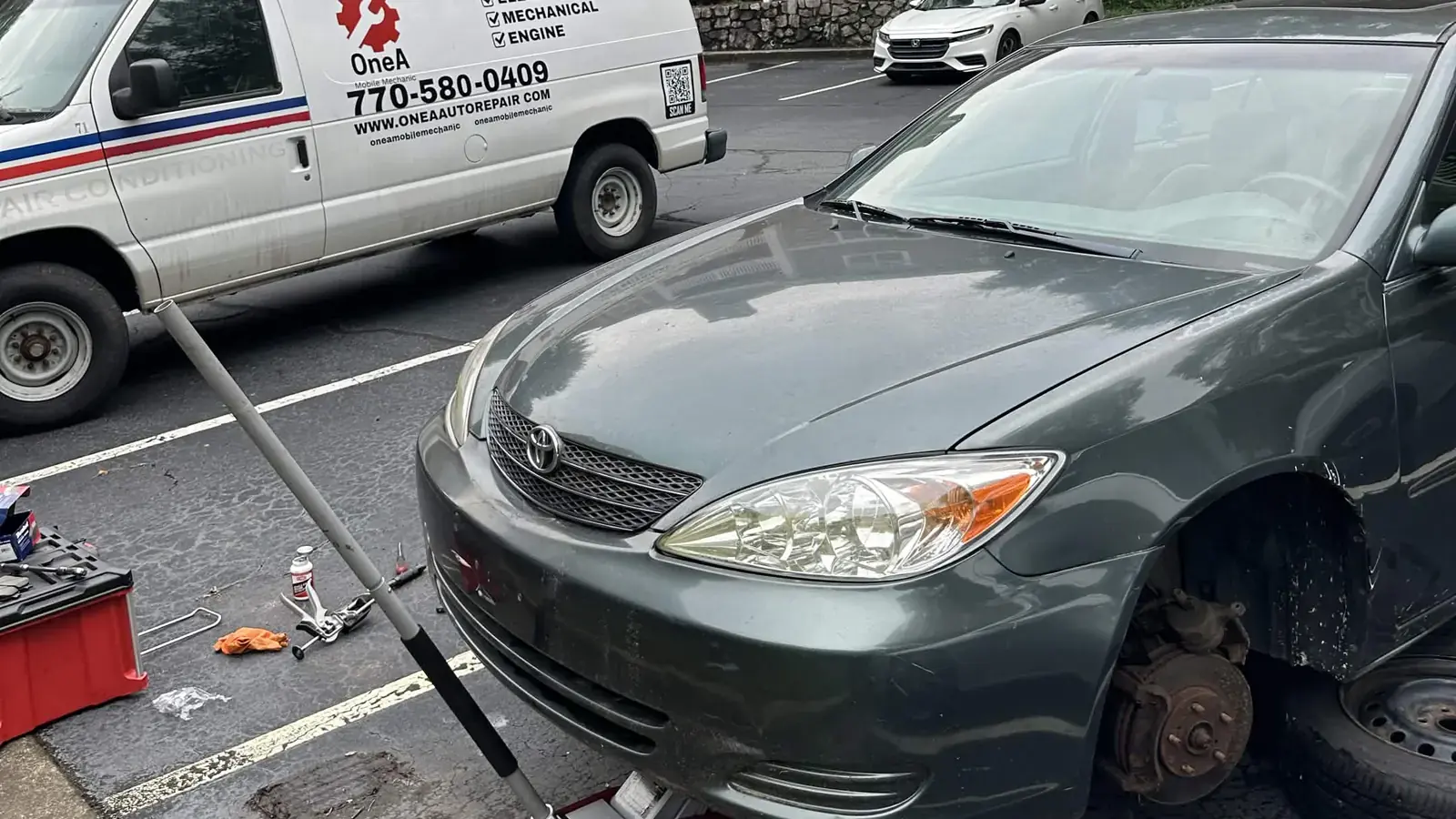 OneA replacing brakes on a car at a customer location, wheel removed and the service van alongside