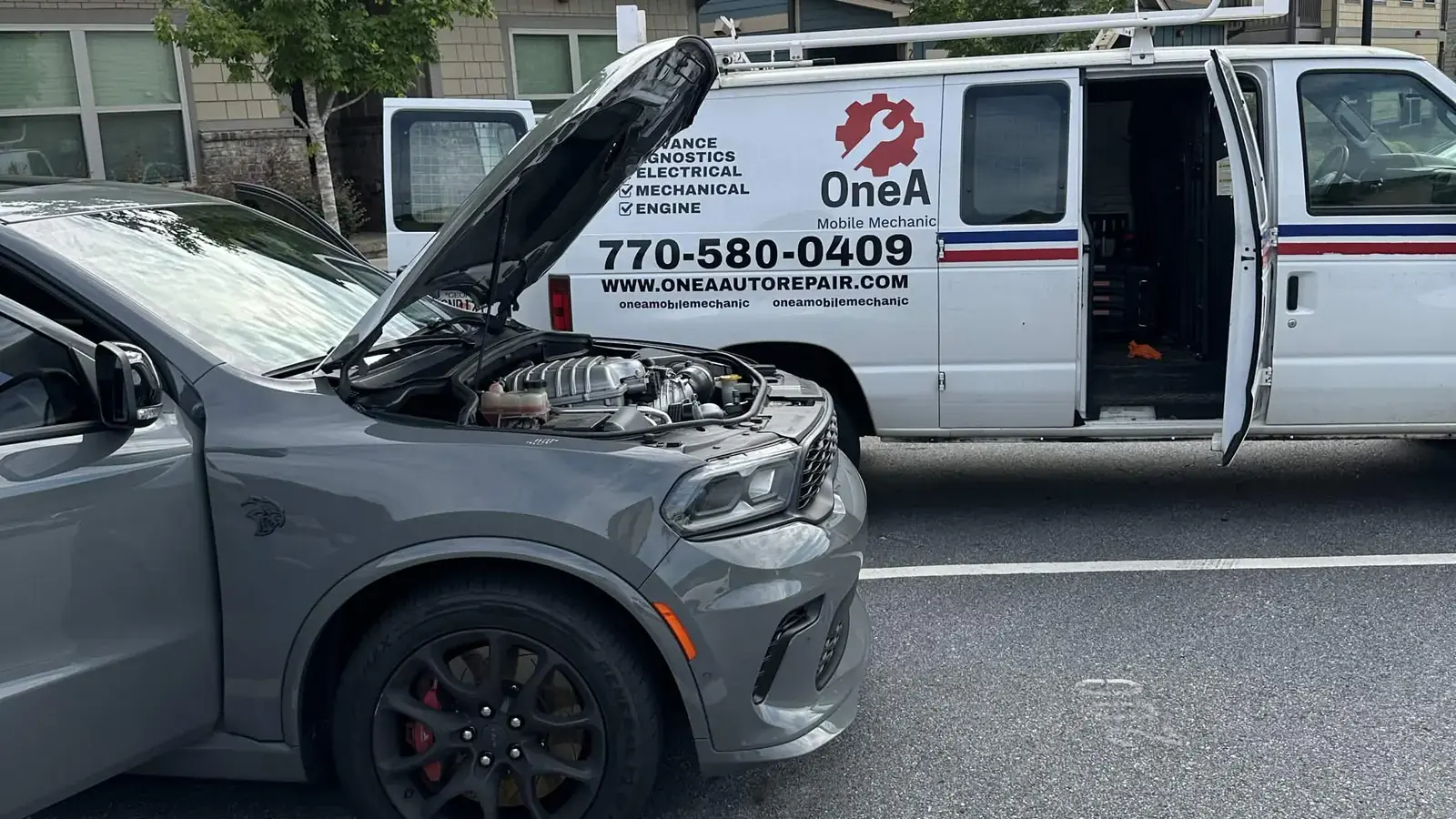OneA diagnosing an engine with the hood up, the mobile service van parked alongside